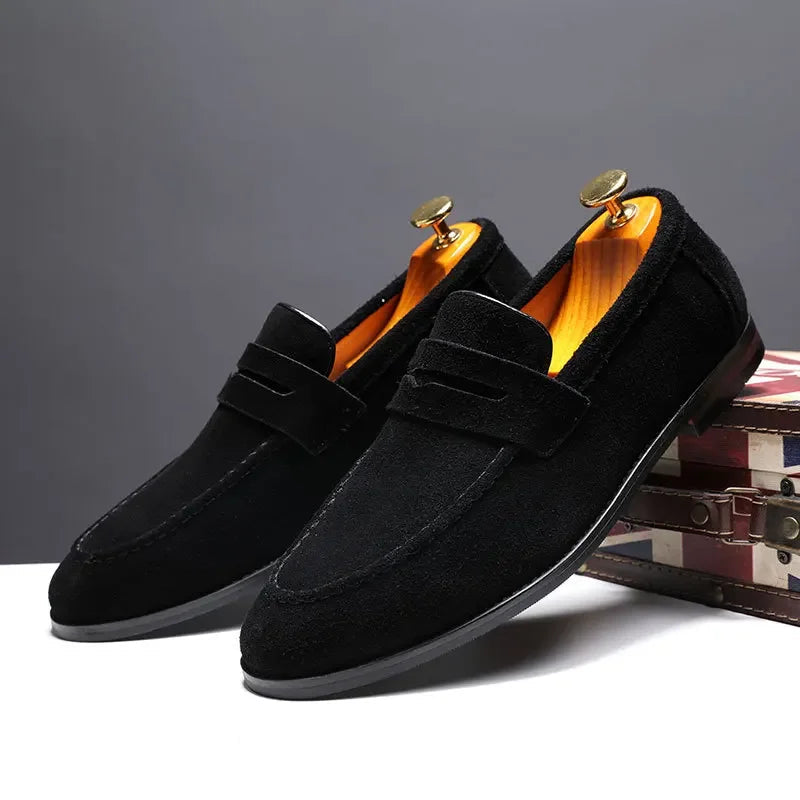 Black loafers with gold accents on a gray background