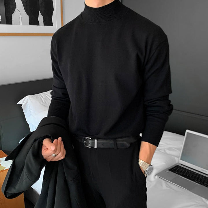 Person wearing a black turtleneck sweater in a bedroom setting.
