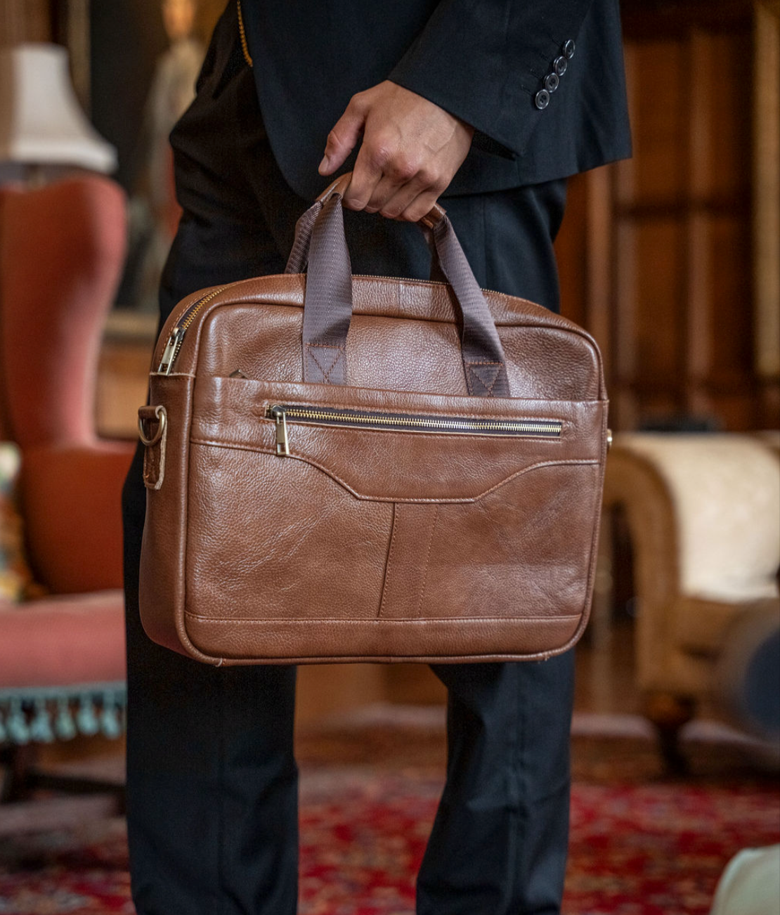 Person holding a brown leather briefcase in an indoor setting