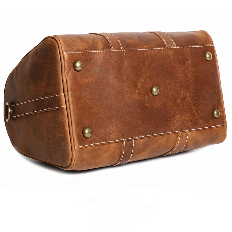 Brown leather duffel bag with gold rivets on a white background