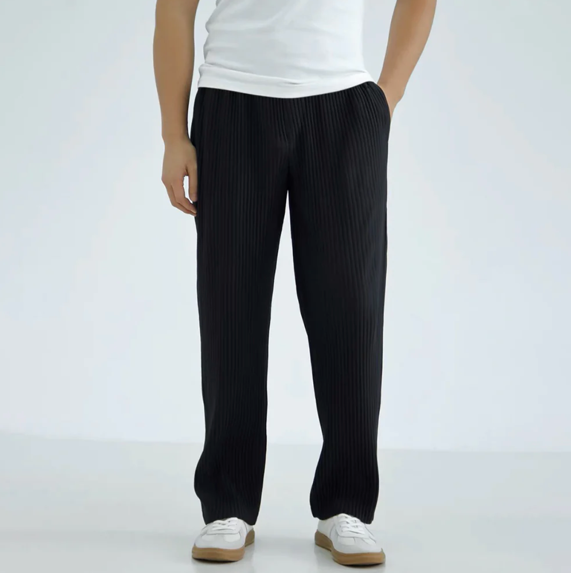 Person wearing black pinstripe pants and a white shirt on a light gray background