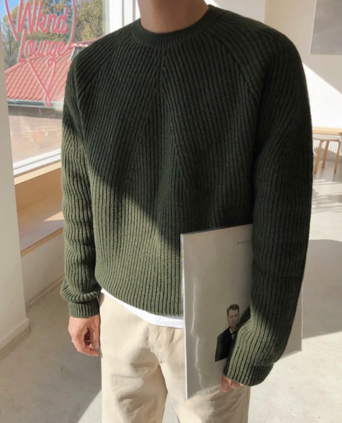 Person wearing a green ribbed sweater in an outdoor setting