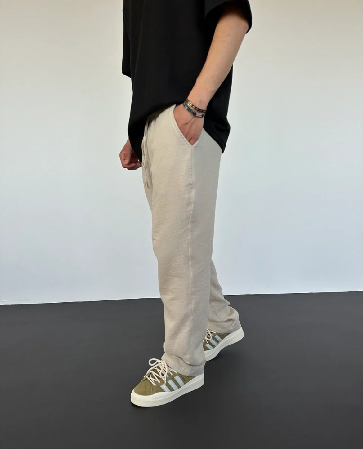 Person wearing beige pants and green sneakers on a plain background