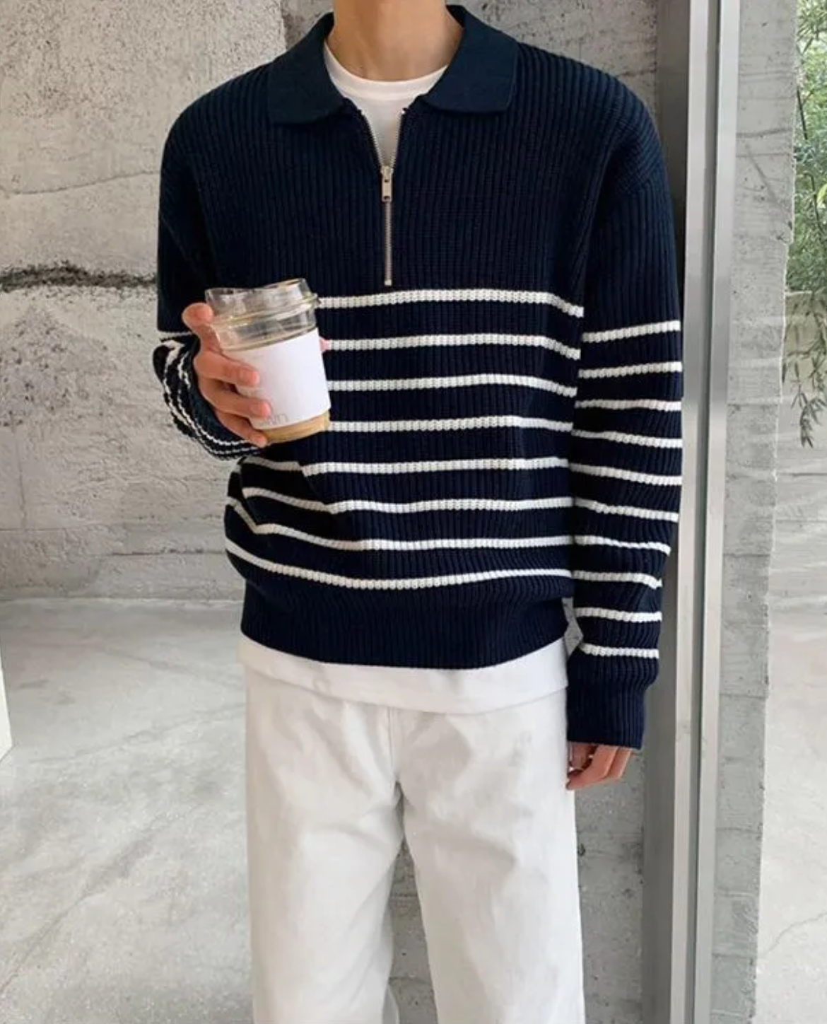 Person wearing a navy and white striped sweater holding a coffee cup.