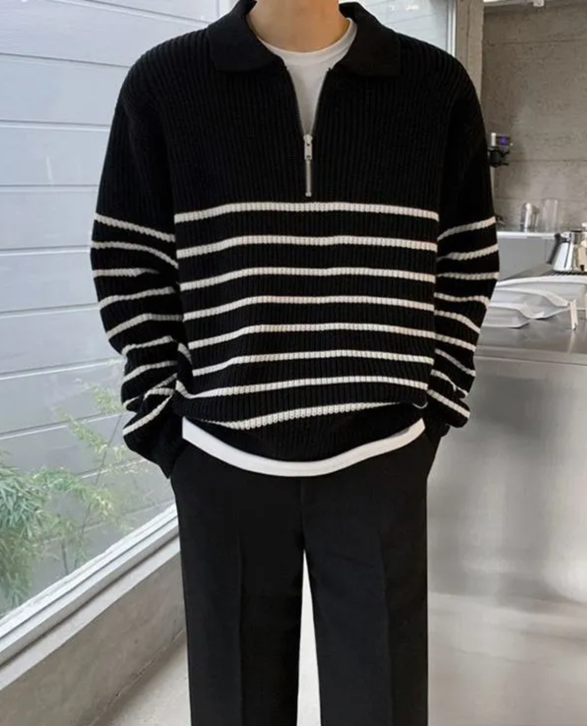 Person wearing a black and white striped sweater in an indoor setting
