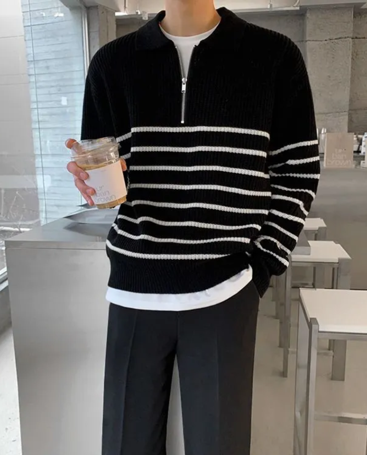 Person wearing a black and white striped sweater holding a jar in an indoor setting.