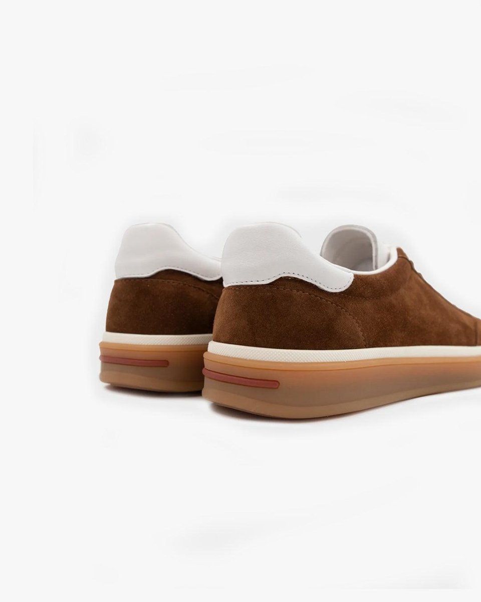 Brown slip-on sneakers with white soles on a light gray background