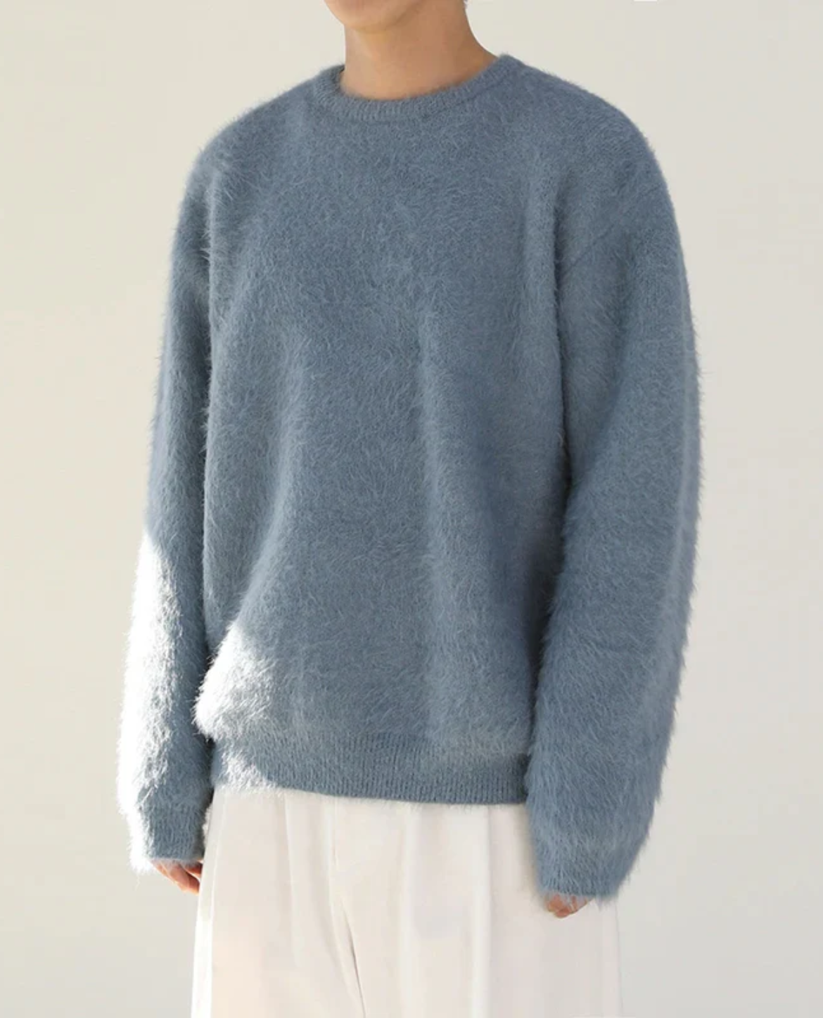 Person wearing a blue sweater against a plain background