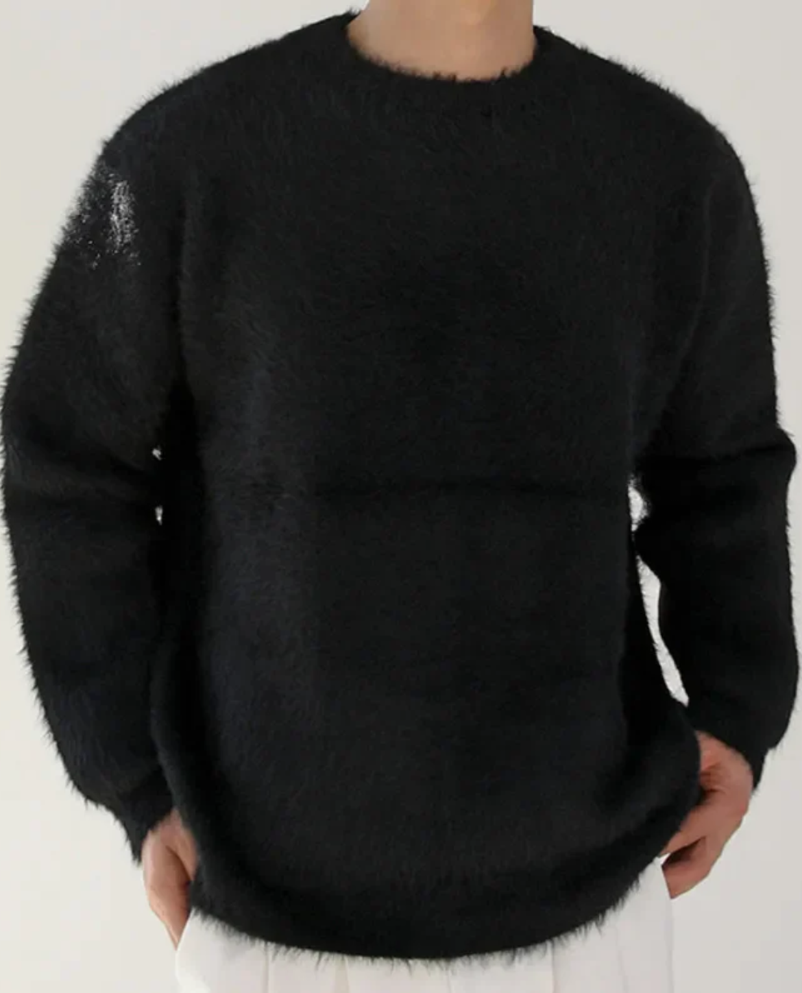 Person wearing a black sweater on a plain background