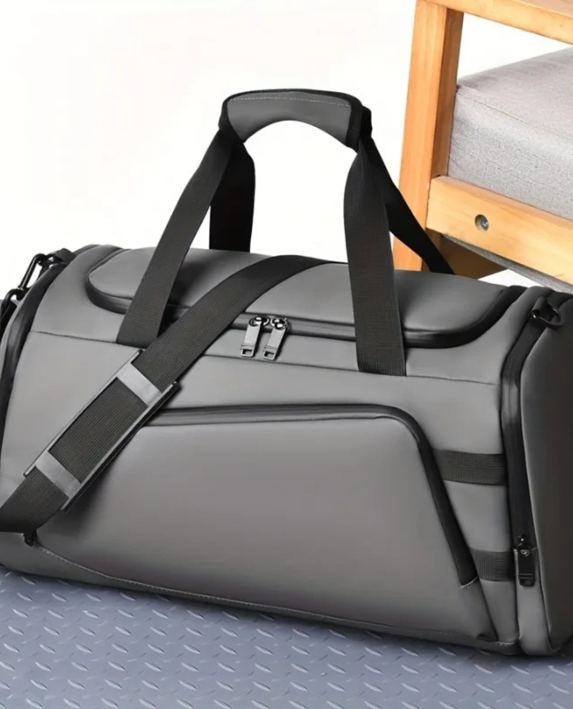 Gray duffel bag with black straps on a textured surface