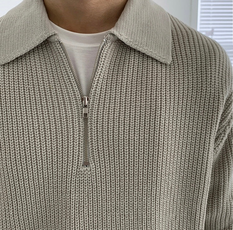 Close-up of a beige knit sweater with a zipper detail.