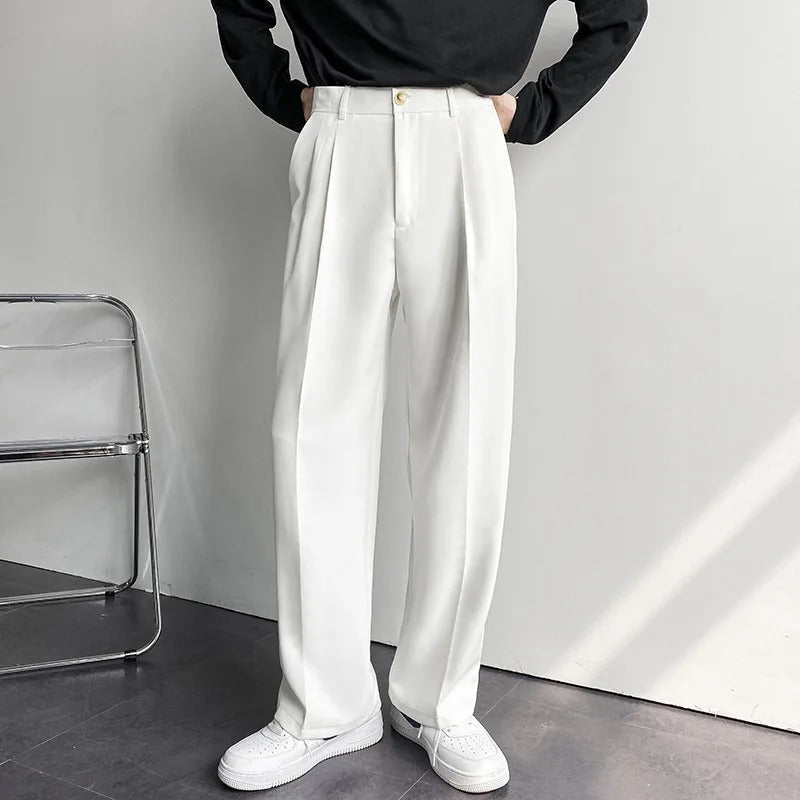 Person wearing white wide-leg pants and a black top in a minimalistic setting.