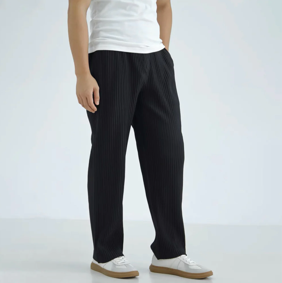 Person wearing black pinstripe pants and a white shirt on a light gray background