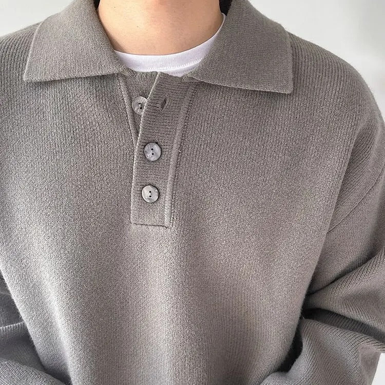 Close-up of a person wearing a gray knitted polo shirt with a white t-shirt underneath.