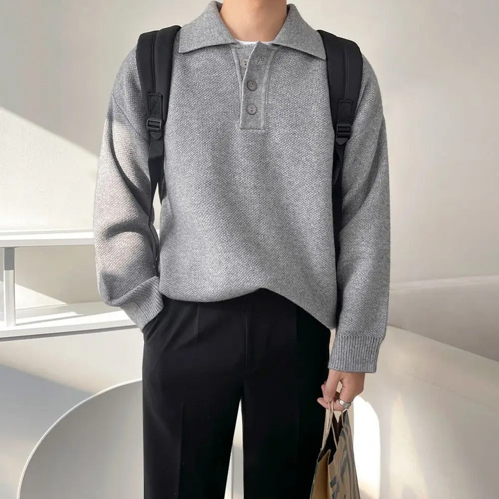 Person wearing a gray sweater and black pants with a backpack indoors.