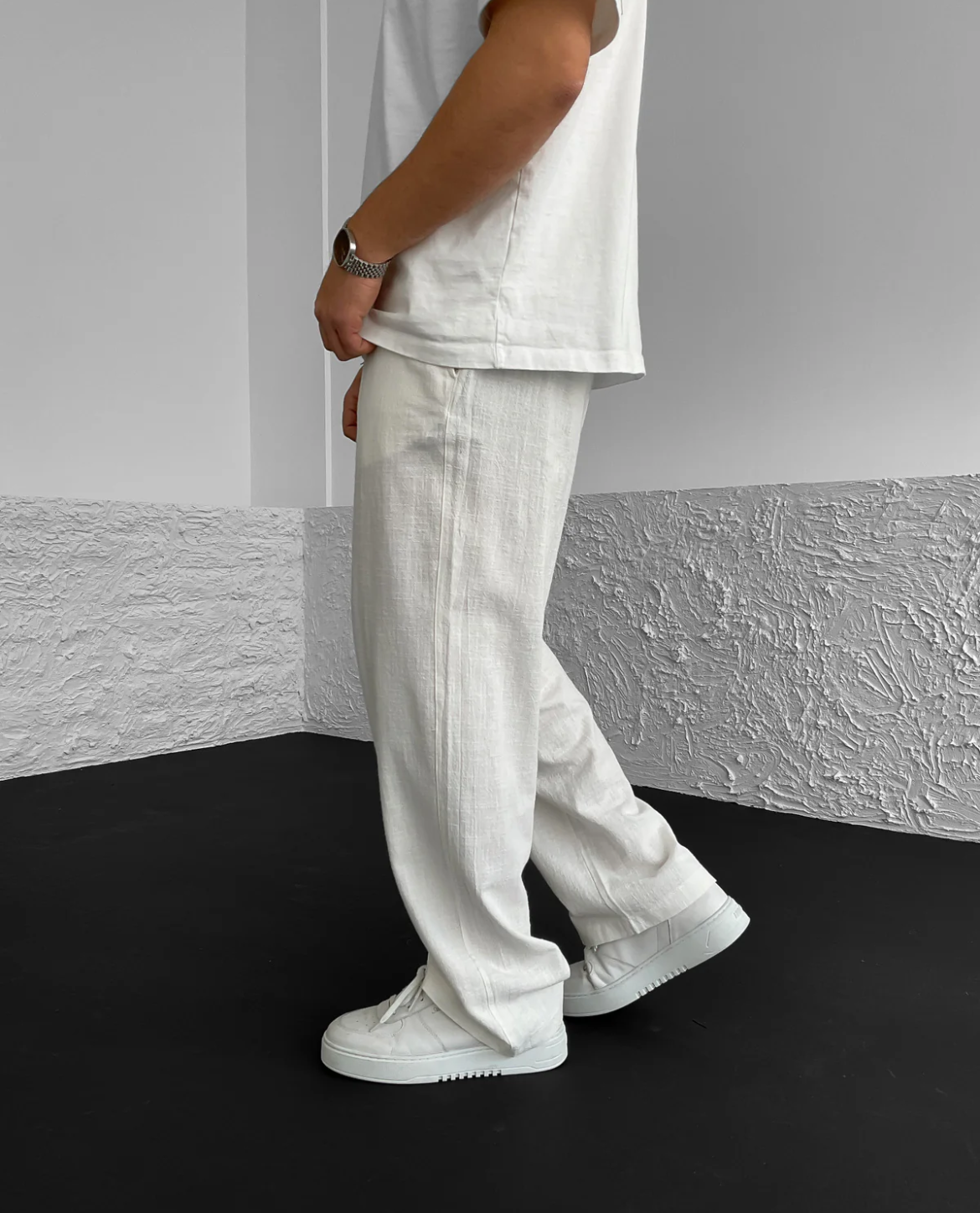 Person wearing a white outfit with pants and shoes in a minimalistic setting
