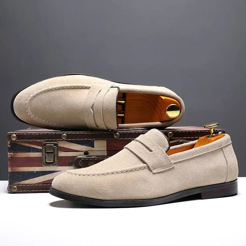 Beige loafers on a small suitcase with a gray background