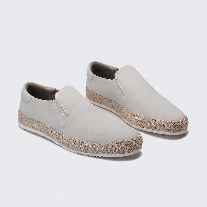 Pair of light gray slip-on shoes with jute sole on a white background