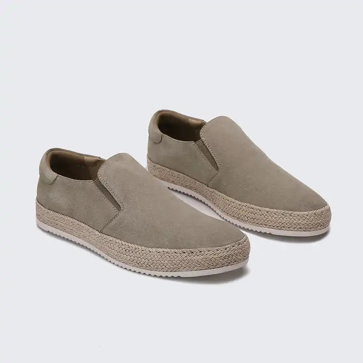 Pair of beige slip-on shoes with jute soles on a light gray background