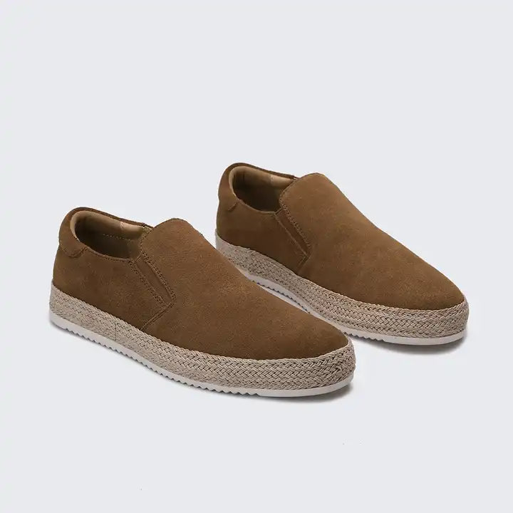 Pair of brown slip-on shoes with textured sole on a light gray background