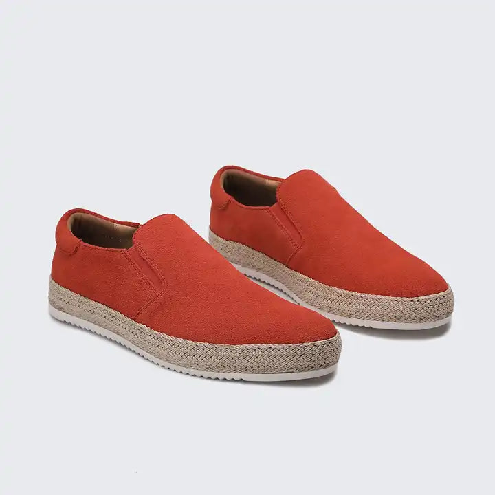 Pair of red slip-on shoes with jute sole on a light gray background