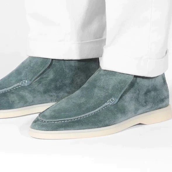 Blue suede shoes worn with white pants on a white background