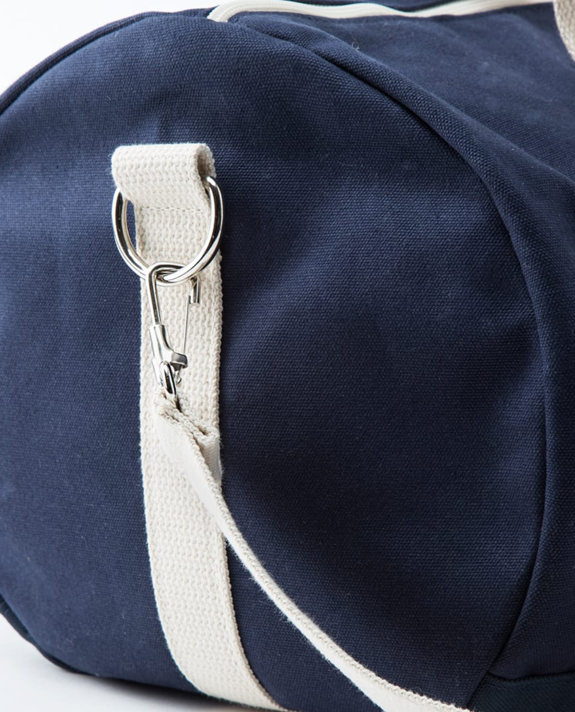 Navy blue duffel bag with a white strap on a light gray background