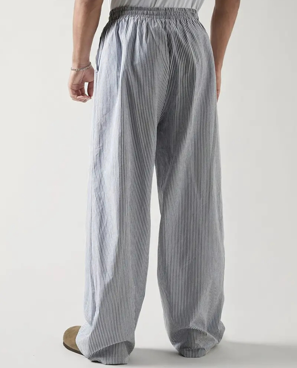 Person wearing gray striped wide-leg pants on a plain background